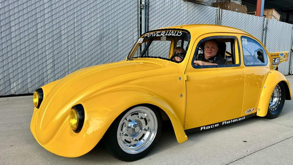 Yellow modified Volkswagen Beetle with racing decals parked at the EMPI 70th Anniversary Open House