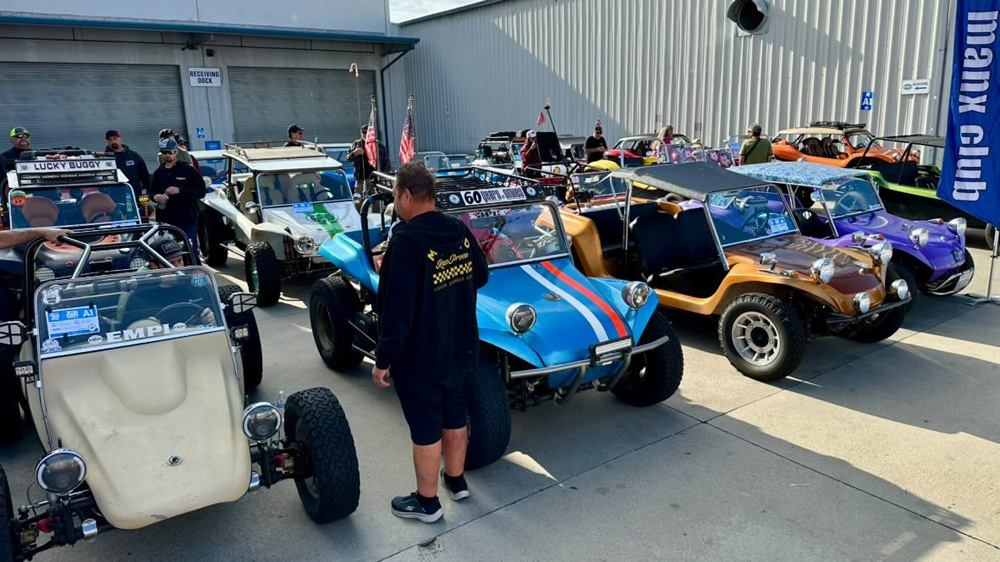 Group of colorful dune buggies parked near a metal building at the EMPI 70th Anniversary Open House